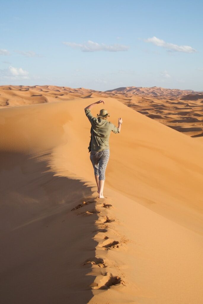 A man walking across a sandy dune in the desert