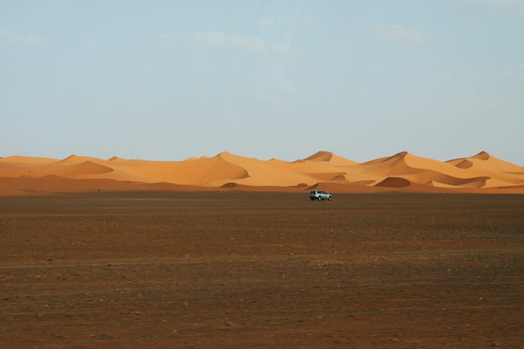 A car drives across a desert landscape.