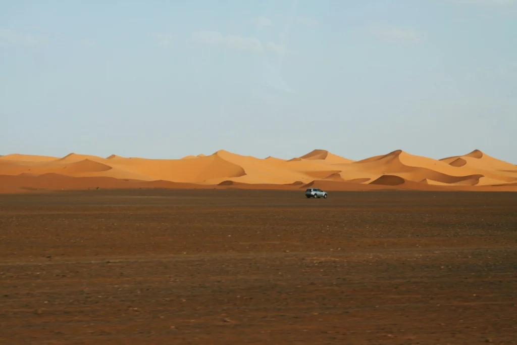 A car drives across a desert landscape.