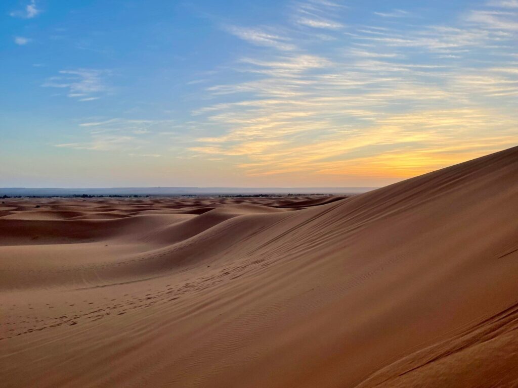 the sun is setting over the sand dunes