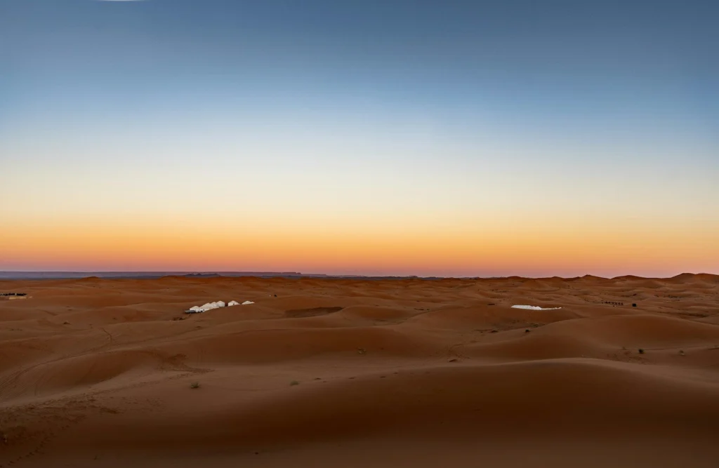 Desert sand dunes under a gradient sky at sunset